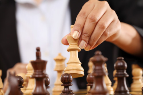 Closeup of business woman hand holding chess king piece